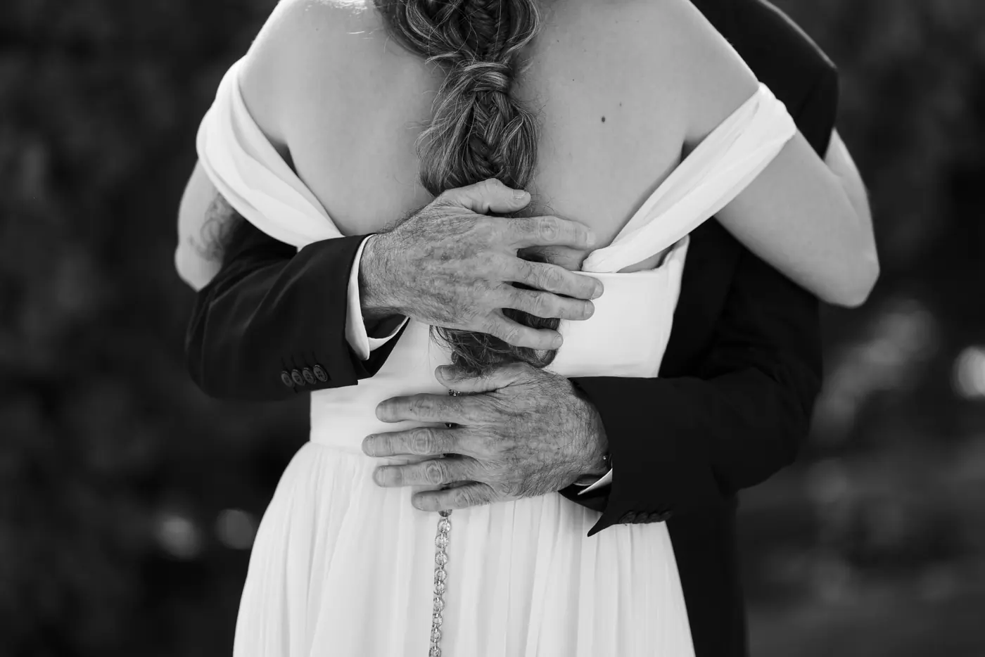 Las manos del novio abrazando a la novia, en blanco y negro