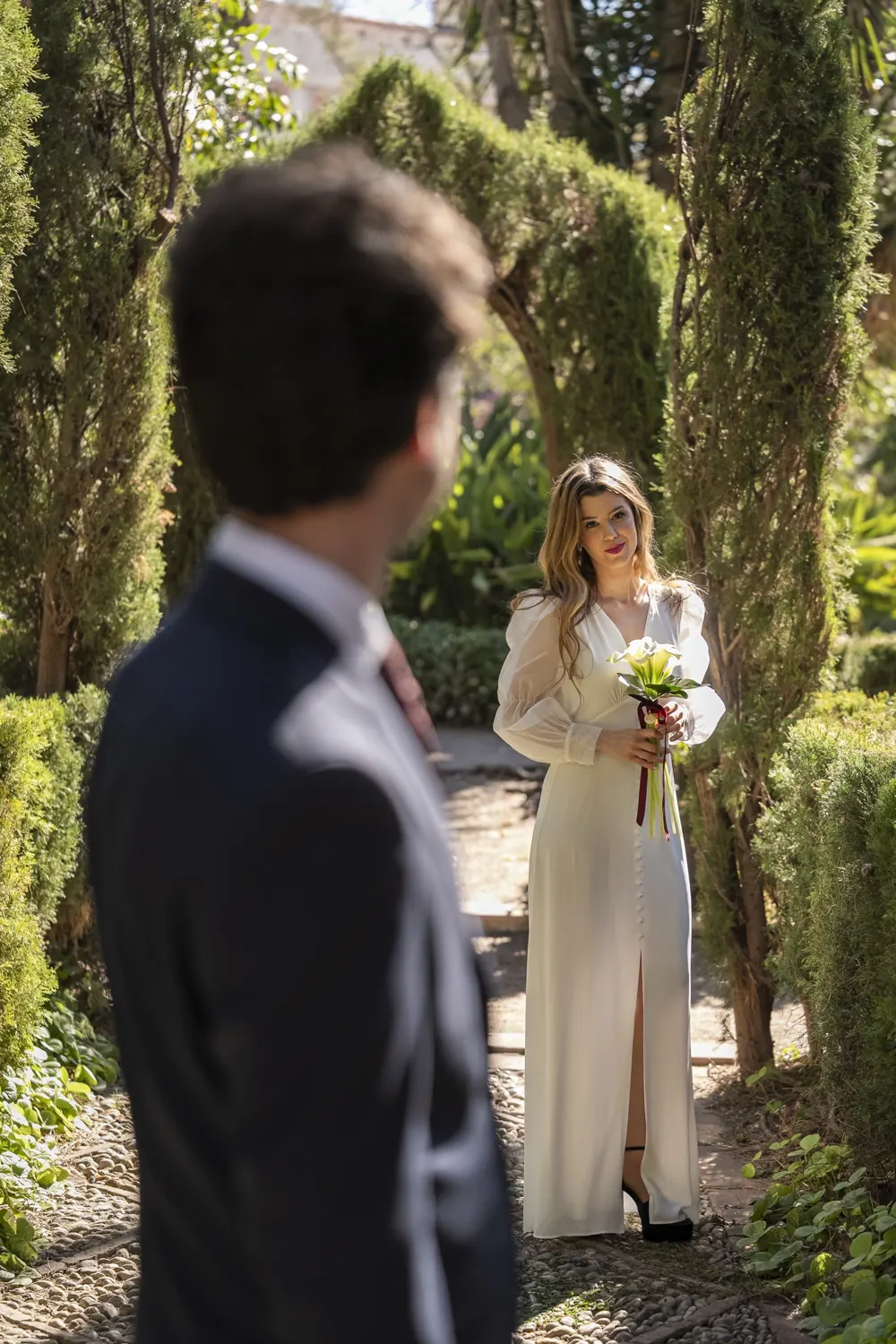 La novia espera con su ramo de calas en un jardín