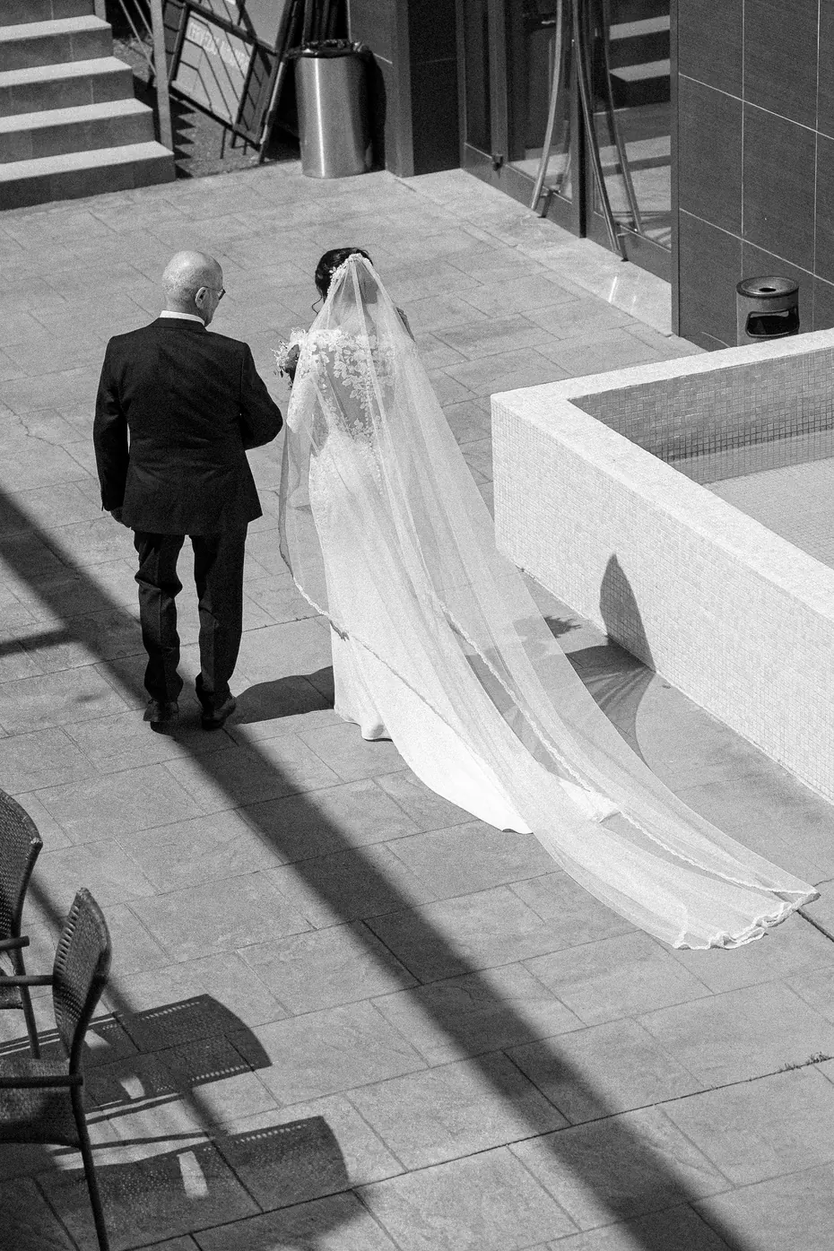 La novia camina del brazo de su padre, en blanco y negro