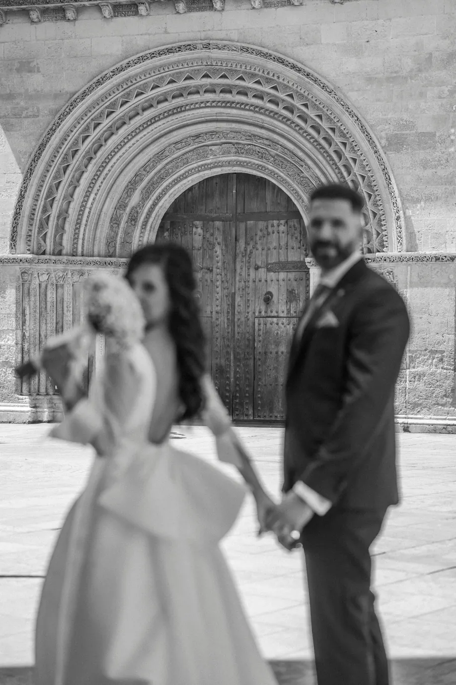 Novios frente a un pórtico de piedra, en blanco y negro