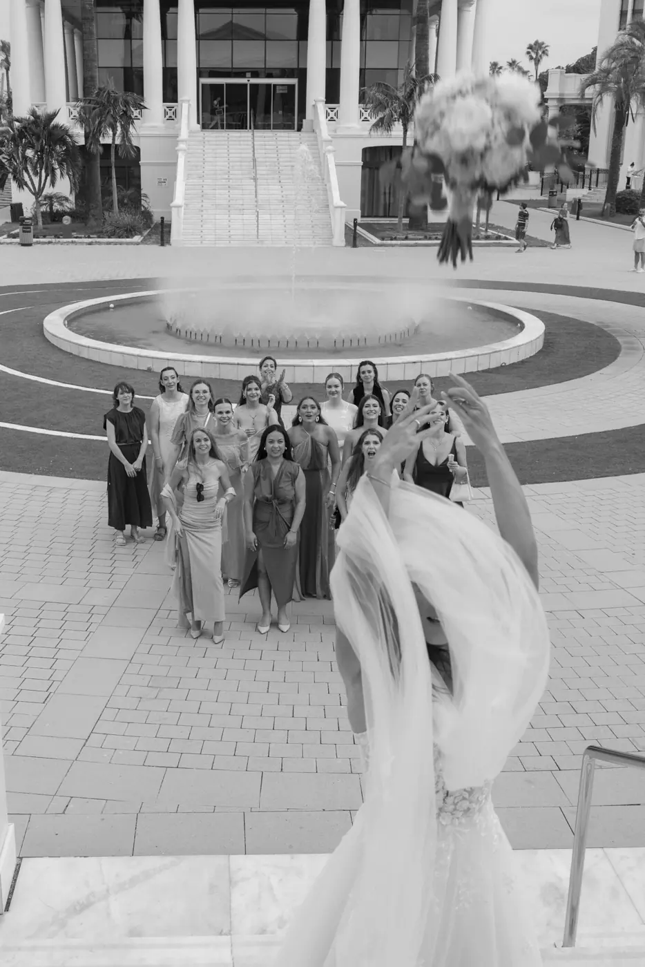 La novia lanza el ramo a sus amigas, en blanco y negro